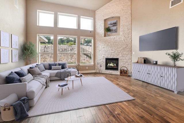 living room featuring a fireplace, a towering ceiling, and hardwood / wood-style floors