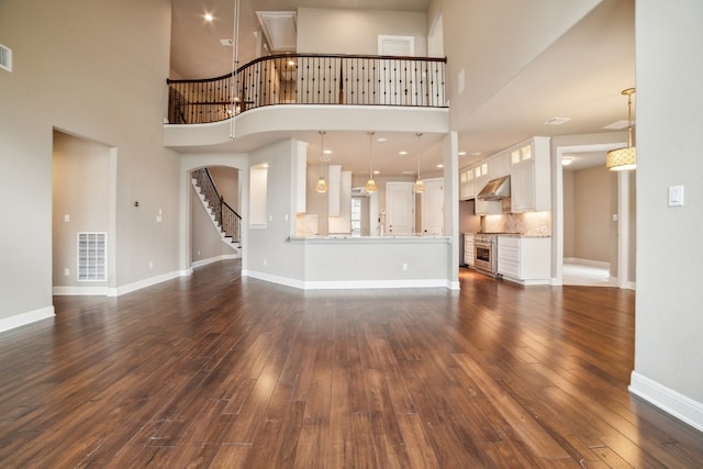 unfurnished living room with dark wood-type flooring and a towering ceiling