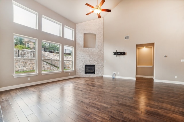 unfurnished living room with high vaulted ceiling, ceiling fan, a healthy amount of sunlight, and dark hardwood / wood-style floors