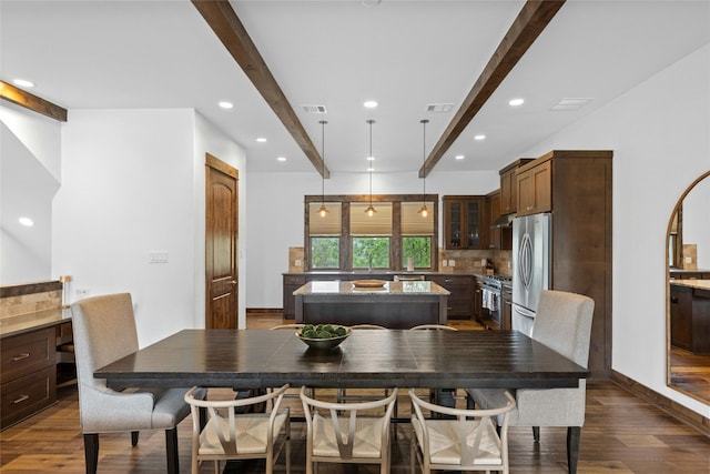 dining area with beamed ceiling and dark hardwood / wood-style floors