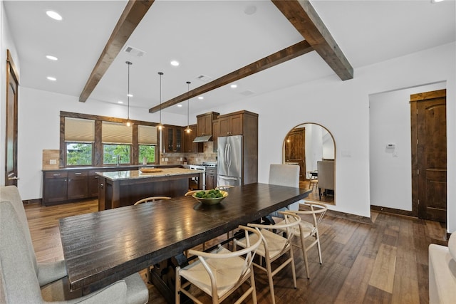 kitchen featuring decorative light fixtures, stainless steel appliances, dark hardwood / wood-style floors, a kitchen island, and beam ceiling