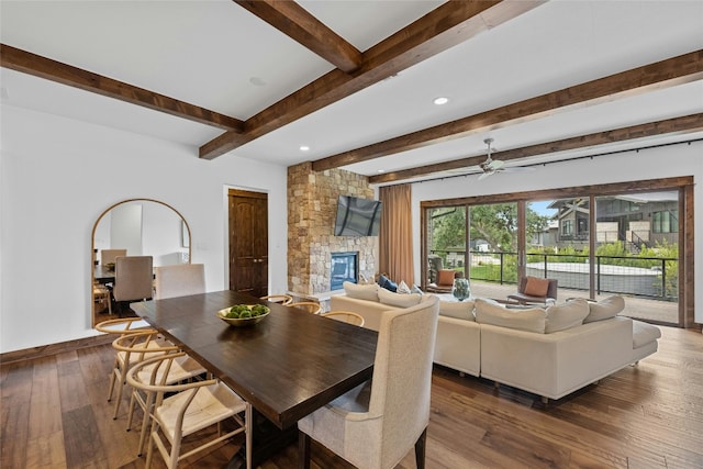 dining area with a fireplace, beamed ceiling, ceiling fan, and dark hardwood / wood-style floors