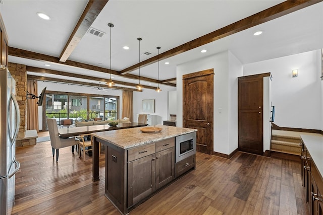 kitchen featuring a kitchen island, hanging light fixtures, stainless steel appliances, dark wood-type flooring, and light stone counters