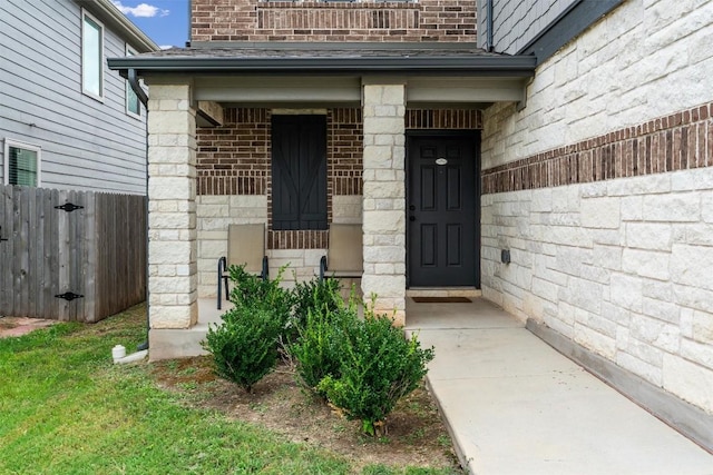 doorway to property with brick siding and fence