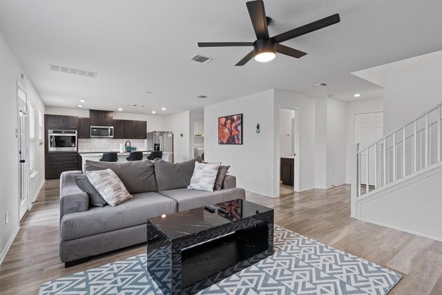 living room with ceiling fan and light wood-type flooring