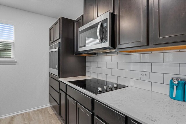 kitchen featuring appliances with stainless steel finishes, light stone counters, dark brown cabinetry, and decorative backsplash