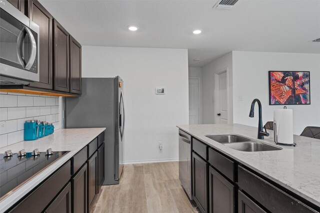 kitchen featuring sink, backsplash, light hardwood / wood-style floors, stainless steel appliances, and dark brown cabinets