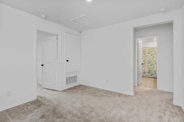 empty room featuring baseboards, visible vents, attic access, and carpet