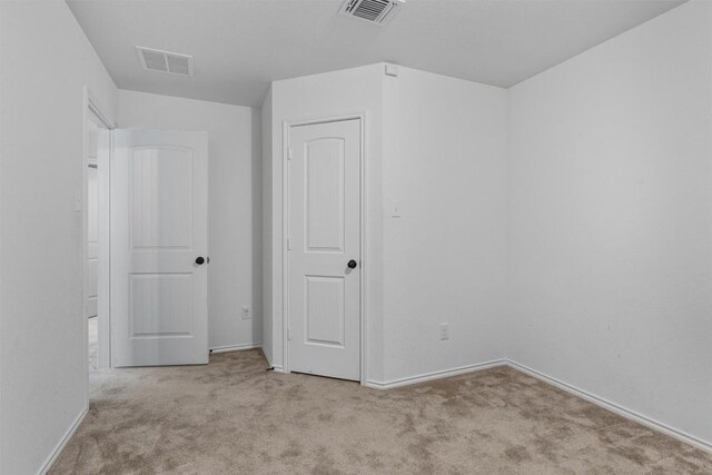 carpeted spare room with visible vents and baseboards