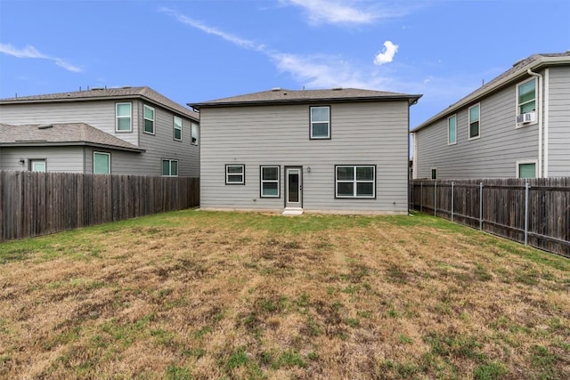 rear view of property with a fenced backyard and a yard