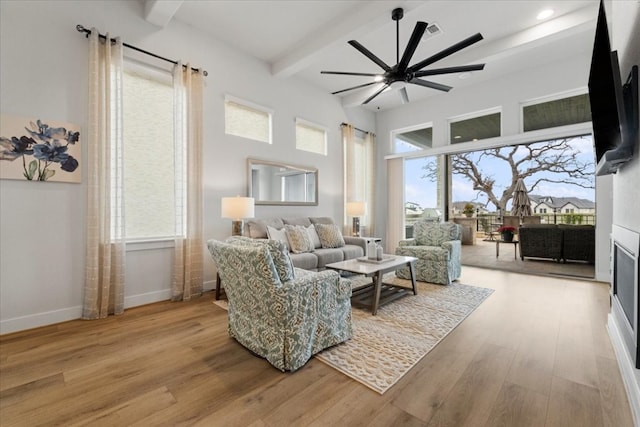 living room featuring hardwood / wood-style flooring, a wealth of natural light, beam ceiling, and ceiling fan