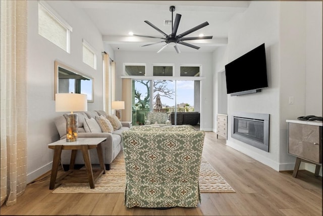 living room with ceiling fan, beam ceiling, and light hardwood / wood-style floors