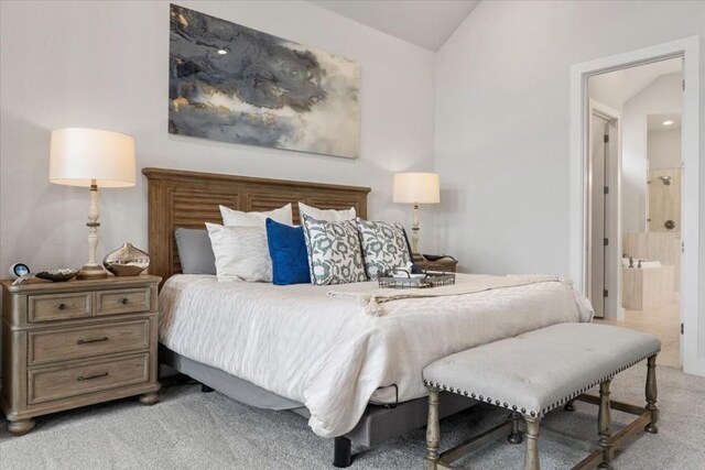 bedroom featuring light carpet, vaulted ceiling, and ensuite bathroom