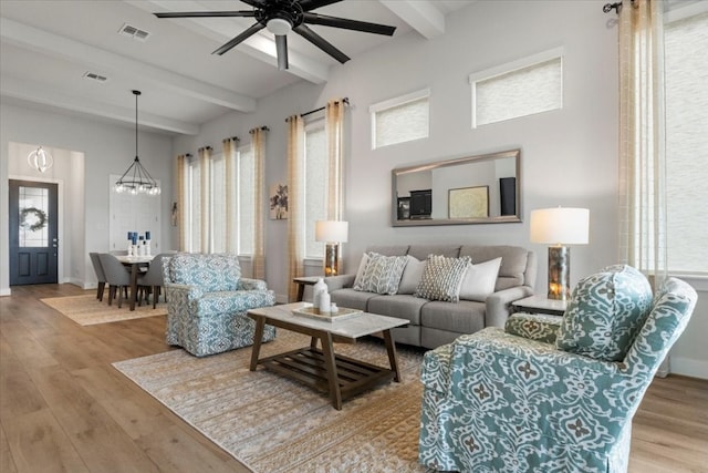 living room featuring ceiling fan with notable chandelier, light hardwood / wood-style floors, and beam ceiling