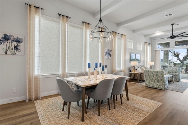 dining area with ceiling fan with notable chandelier, beam ceiling, and hardwood / wood-style flooring