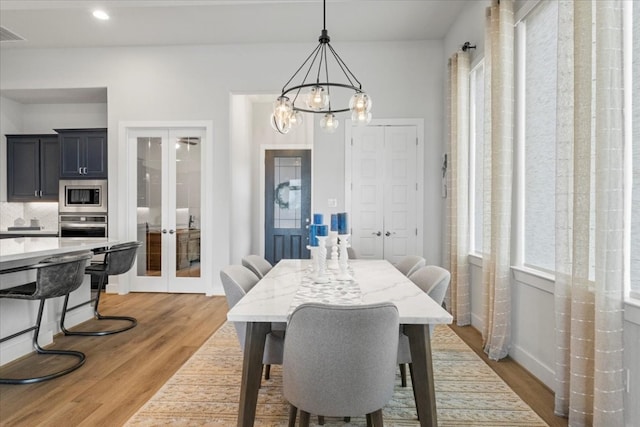 dining area featuring light hardwood / wood-style flooring, an inviting chandelier, and french doors