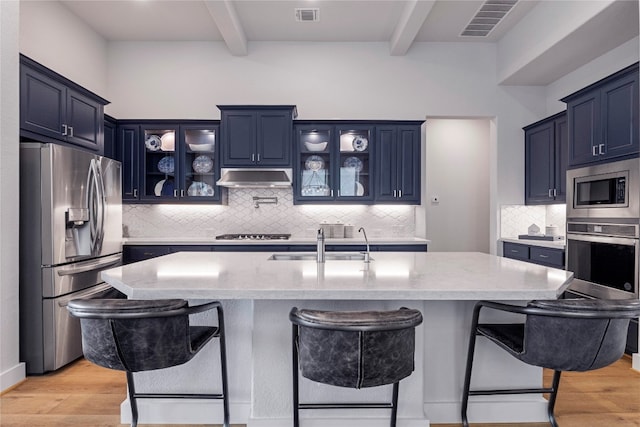 kitchen featuring light wood-type flooring, a breakfast bar area, stainless steel appliances, and blue cabinetry