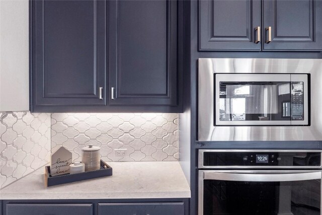 kitchen featuring blue cabinets, stainless steel appliances, and decorative backsplash