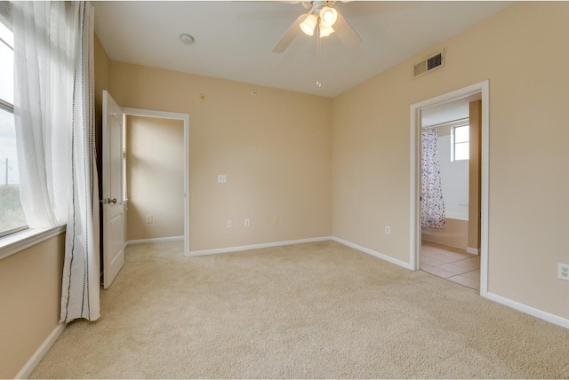 unfurnished bedroom with light colored carpet, ceiling fan, and ensuite bathroom