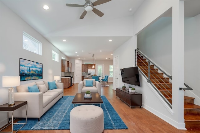 living room with ceiling fan, light hardwood / wood-style floors, and lofted ceiling