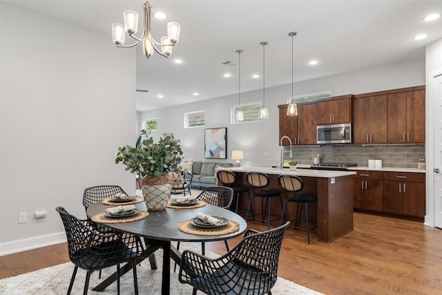 dining area featuring light hardwood / wood-style flooring, a notable chandelier, and sink