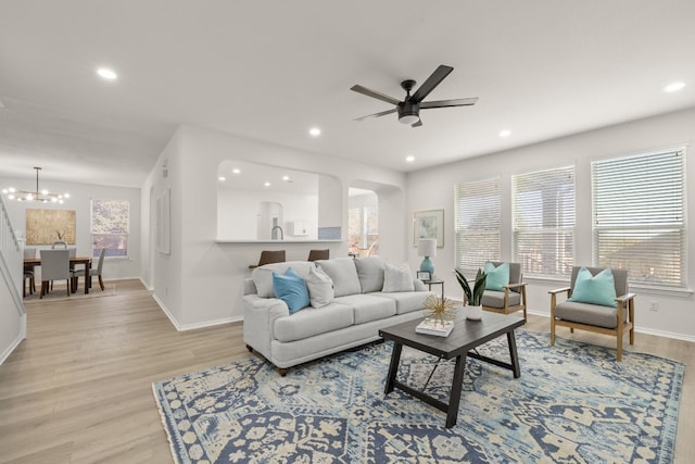 living room featuring ceiling fan with notable chandelier and light hardwood / wood-style floors