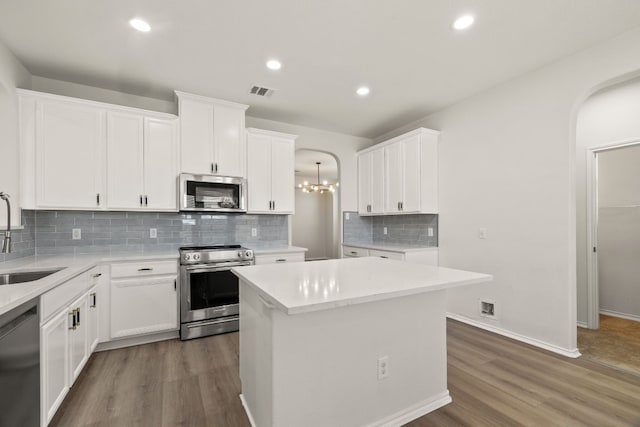 kitchen with white cabinets, a center island, appliances with stainless steel finishes, sink, and dark hardwood / wood-style floors