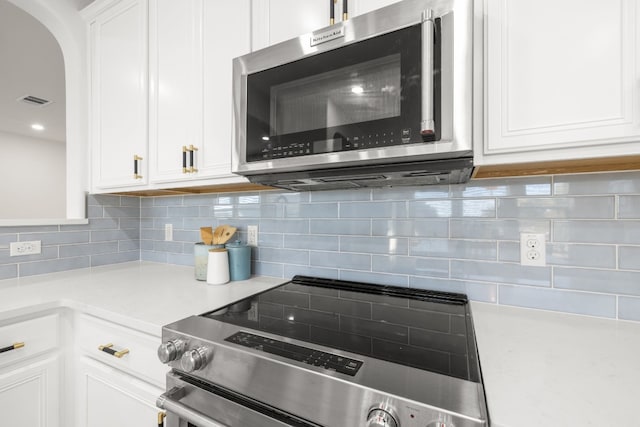 kitchen with backsplash, stainless steel appliances, and white cabinetry