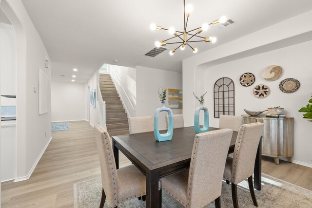 dining space with light wood-type flooring and an inviting chandelier