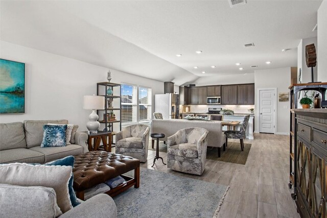 living room with lofted ceiling and light hardwood / wood-style flooring