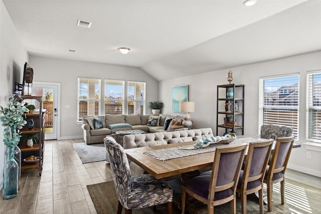 dining area with light wood-type flooring, vaulted ceiling, and a wealth of natural light