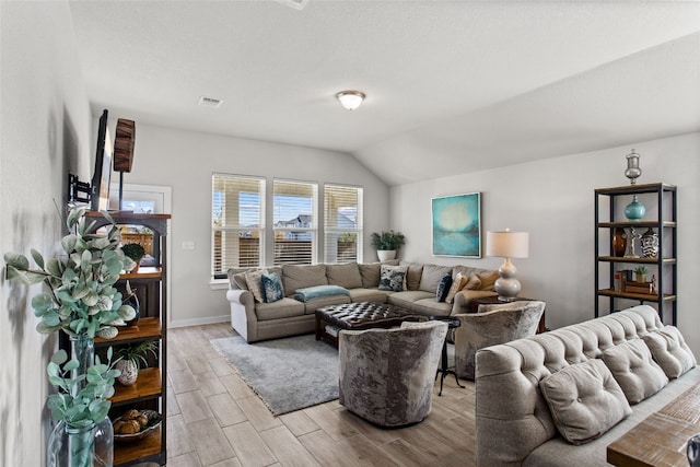 living room featuring lofted ceiling and light hardwood / wood-style floors