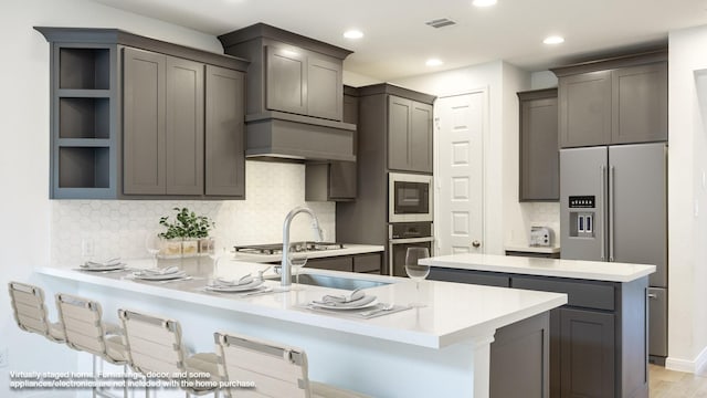 kitchen featuring decorative backsplash, a breakfast bar area, kitchen peninsula, and appliances with stainless steel finishes