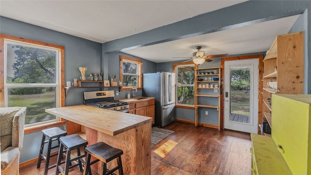 kitchen with a breakfast bar area, dark hardwood / wood-style flooring, stainless steel appliances, sink, and ceiling fan