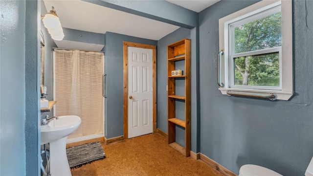 bathroom featuring walk in shower, toilet, and sink