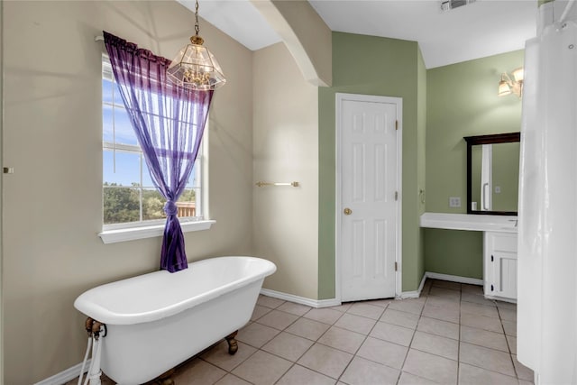 bathroom with a tub, vanity, and tile patterned floors