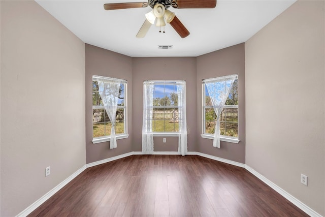 empty room featuring dark wood-type flooring, plenty of natural light, and ceiling fan