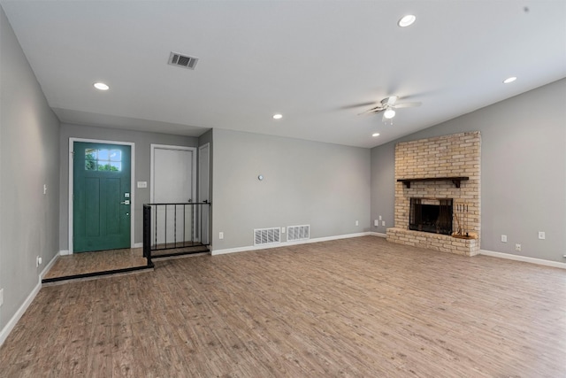 unfurnished living room featuring lofted ceiling, ceiling fan, light hardwood / wood-style floors, and a brick fireplace