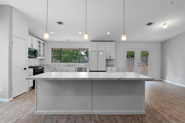 kitchen with black appliances, white cabinetry, and a wealth of natural light