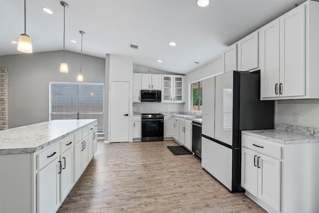 kitchen featuring white cabinetry, hanging light fixtures, appliances with stainless steel finishes, lofted ceiling, and light hardwood / wood-style floors