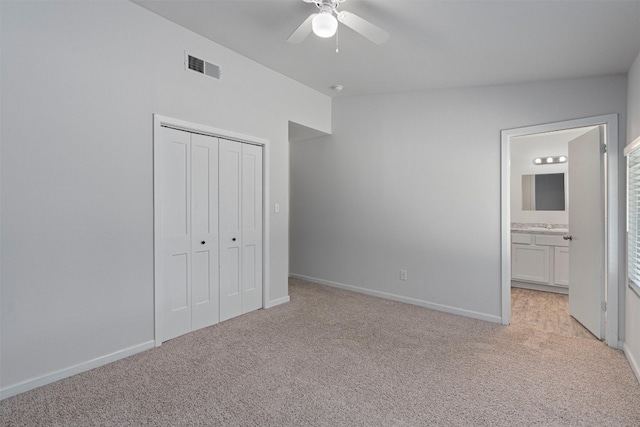 unfurnished bedroom with vaulted ceiling, a closet, ensuite bath, light colored carpet, and ceiling fan