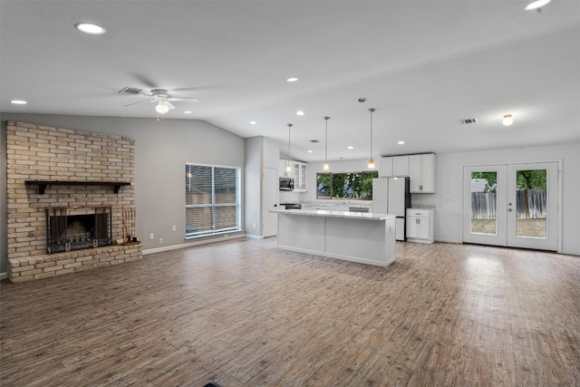 unfurnished living room featuring a brick fireplace, hardwood / wood-style floors, ceiling fan, and a healthy amount of sunlight