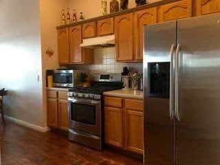 kitchen with stainless steel appliances, dark hardwood / wood-style floors, and tasteful backsplash