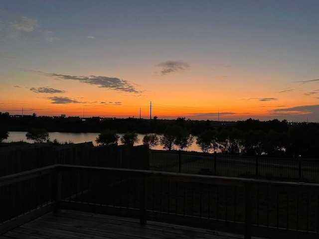 deck at dusk featuring a water view