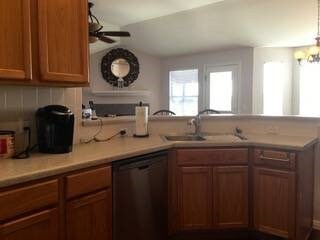 kitchen with ceiling fan with notable chandelier, dishwasher, kitchen peninsula, and sink