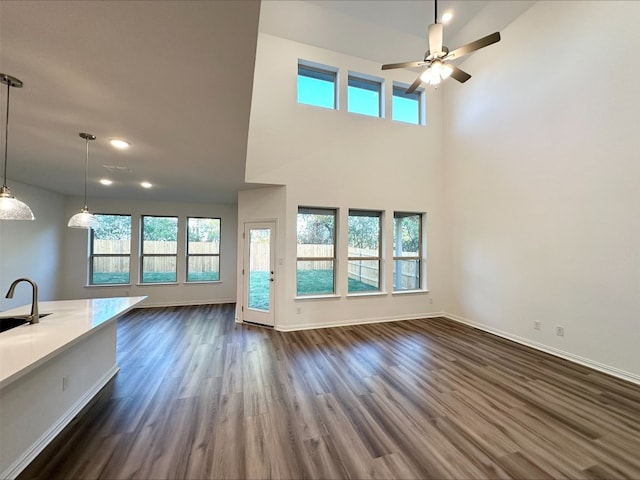 unfurnished living room with a towering ceiling, dark hardwood / wood-style floors, ceiling fan, and sink