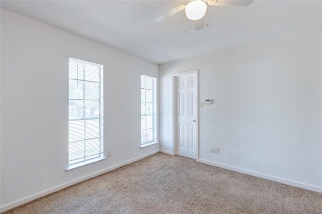 unfurnished room with plenty of natural light, ceiling fan, and light carpet