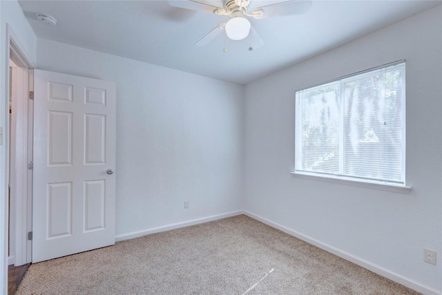 spare room featuring light colored carpet and ceiling fan