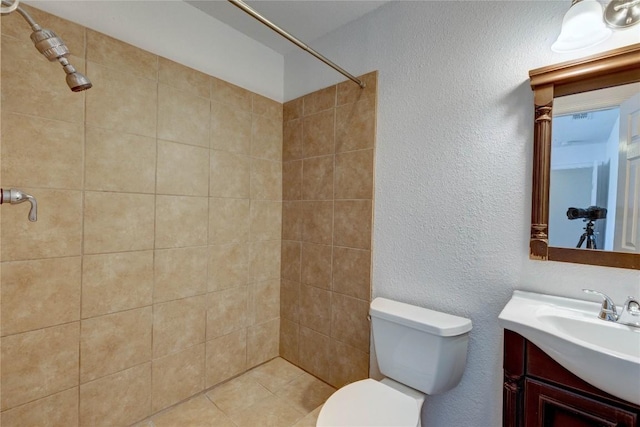 bathroom featuring tiled shower, vanity, and toilet