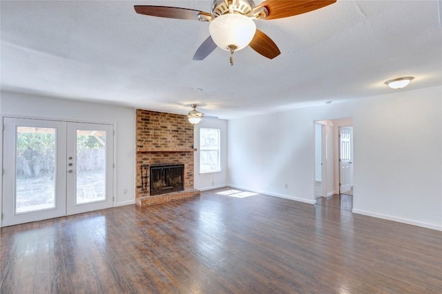 unfurnished living room with french doors, a brick fireplace, a textured ceiling, ceiling fan, and dark hardwood / wood-style floors